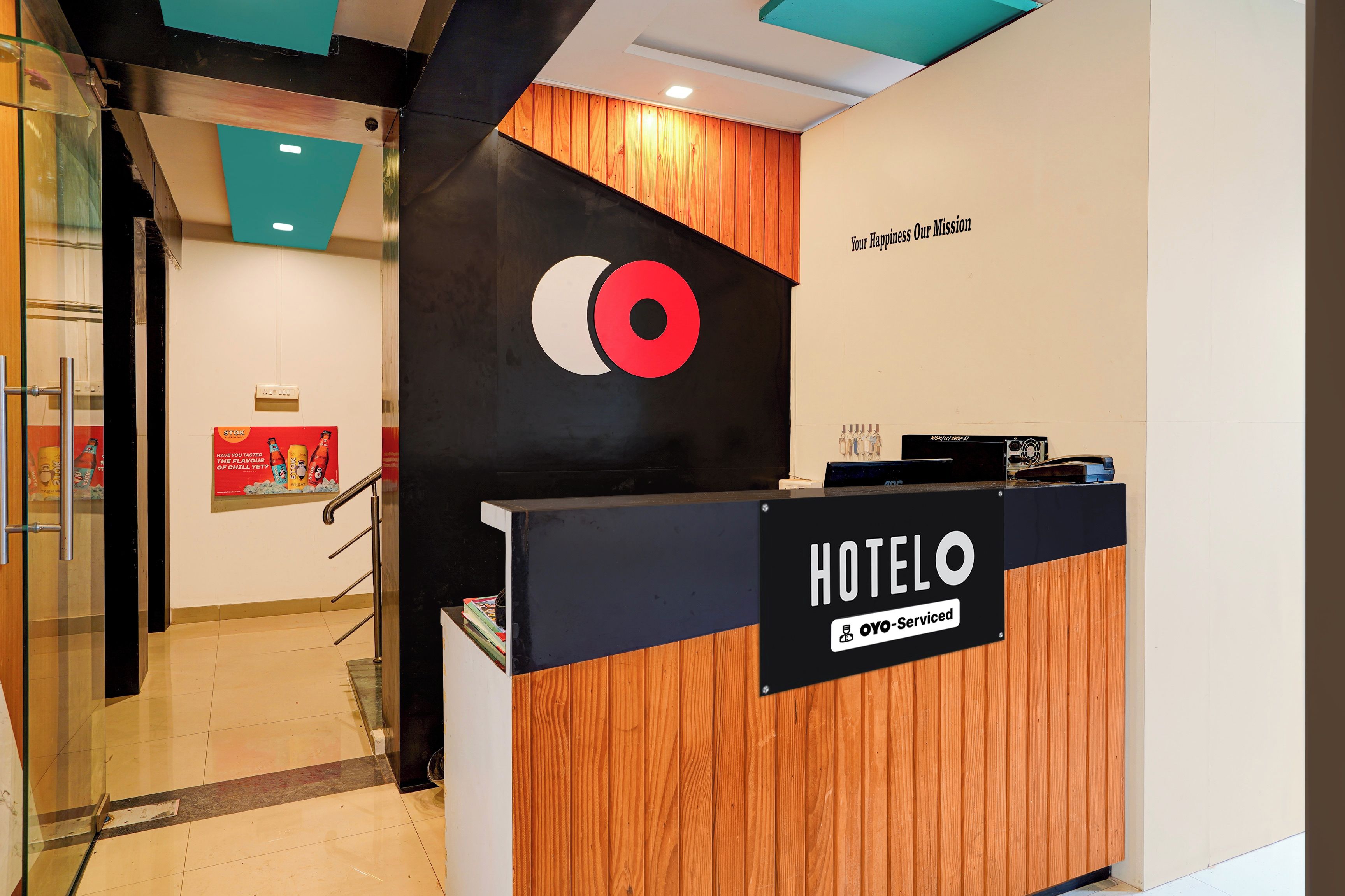 Mostrador de recepción de hotel con detalles de madera y un letrero que indica que el servicio es proporcionado por OYO.