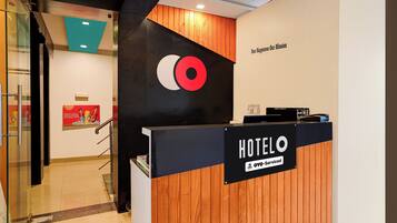 Mostrador de recepción de hotel con detalles de madera y un letrero que indica que el servicio es proporcionado por OYO.