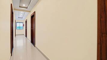 A hallway with a tiled floor, wooden doors, and a fire extinguisher on the wall.