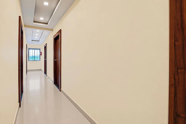 A hallway with a tiled floor, wooden doors, and a fire extinguisher on the wall.