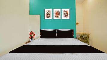Un dormitorio con una cama, una mesita de noche, un jarrón con flores y tres cuadros en la pared.