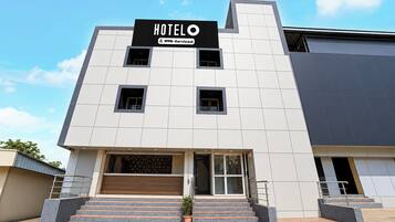 A modern hotel building with a sign indicating it is serviced by OYO.