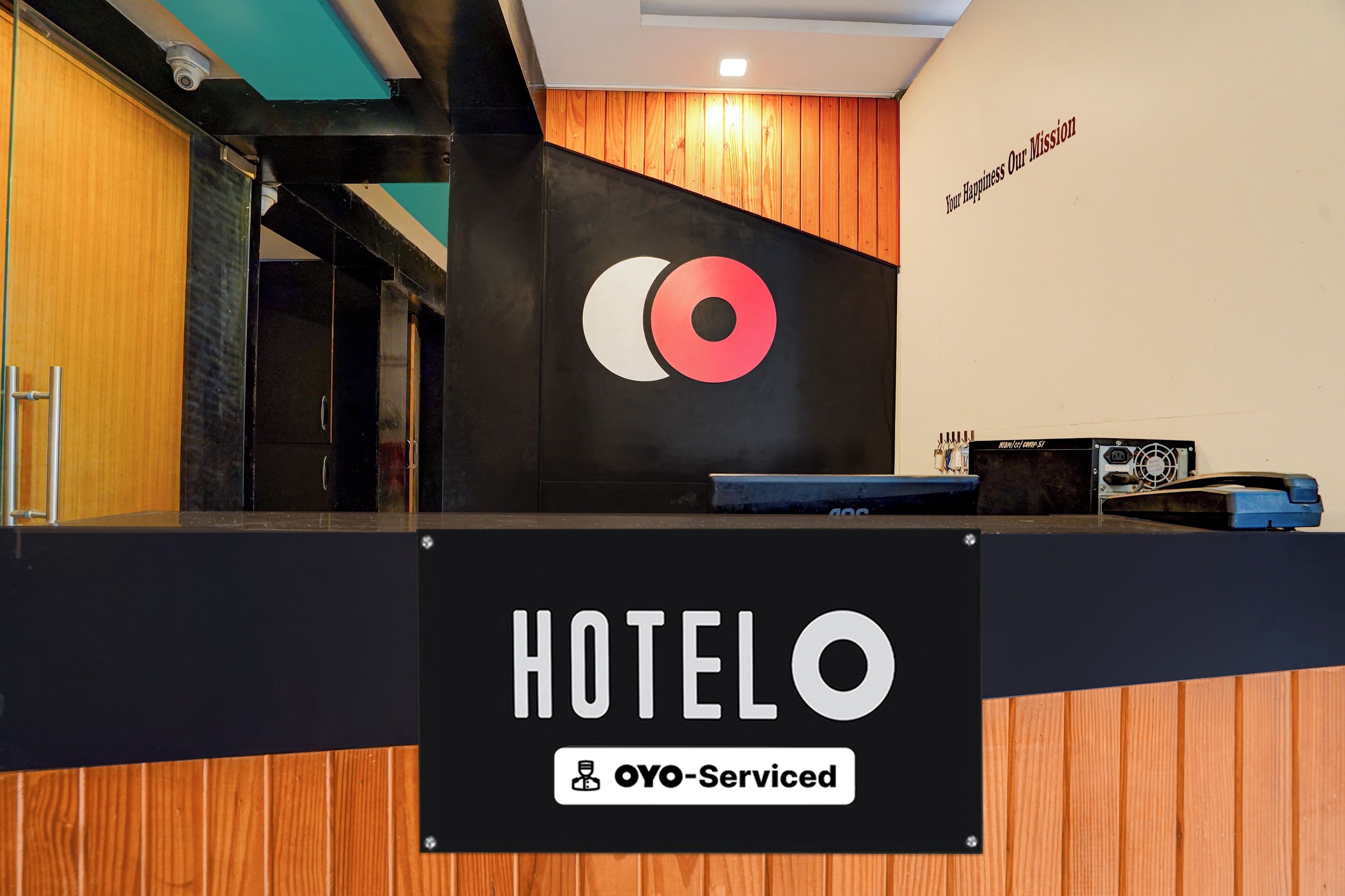 A hotel reception desk with a sign reading 'HOTELO' and 'OYO-Serviced'.