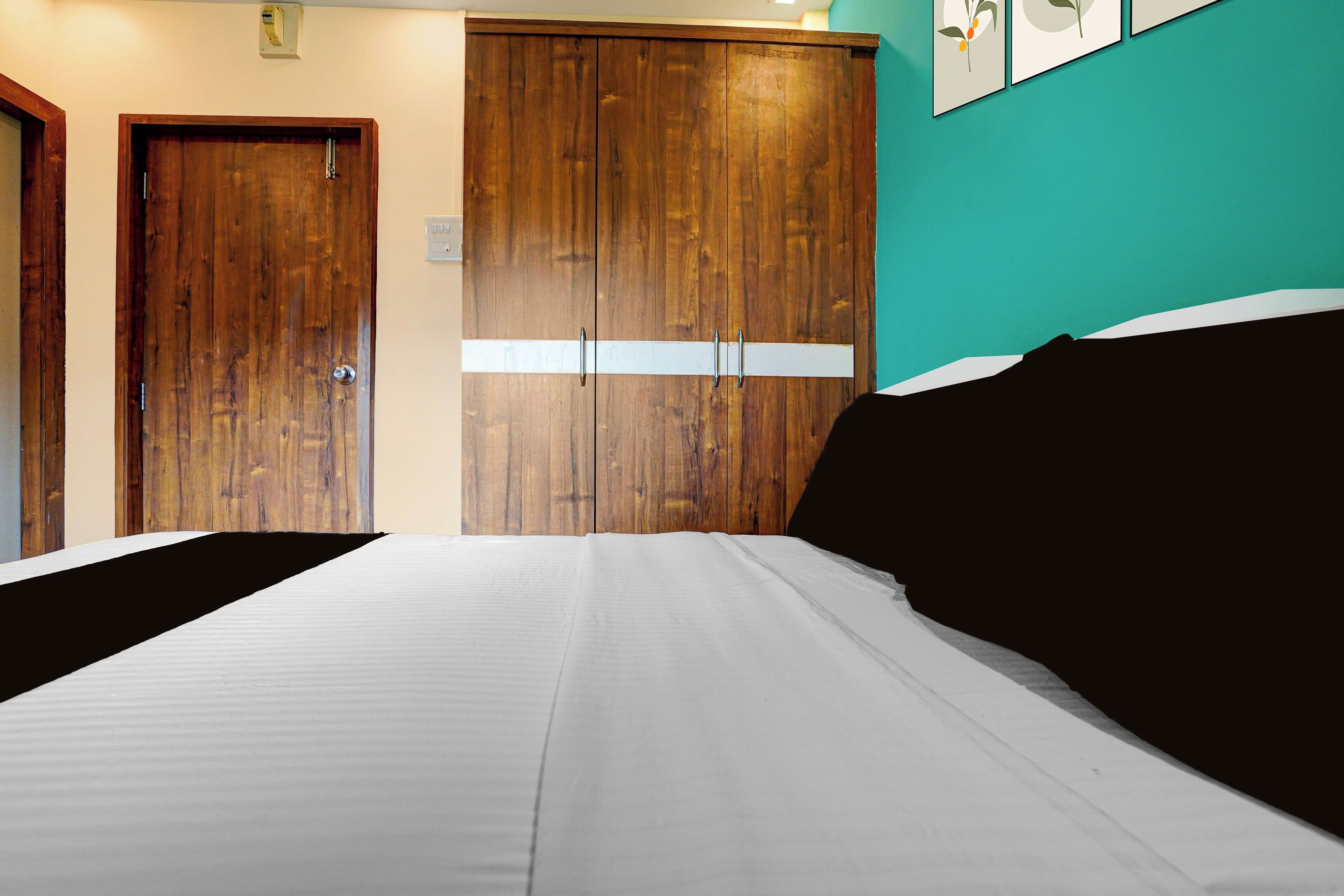 Un dormitorio con una cama, un armario de madera y una pared verde azulado.