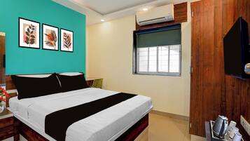 A bedroom with a bed, a window, an air conditioning unit, and wall art.