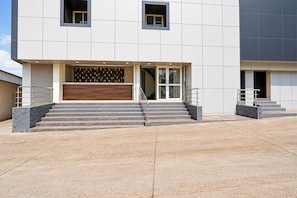 A modern building with a flat facade, large windows, and a set of stairs leading to a door.