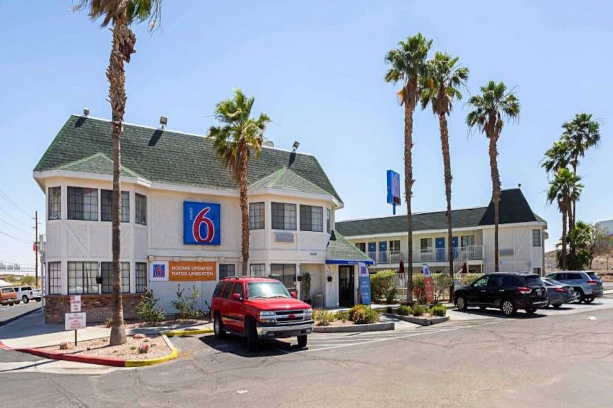 A motel with a '6' sign, multiple parking spaces, and palm trees.