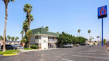 Un motel avec un parking, un bâtiment doté d’un toit végétalisé et des palmiers.