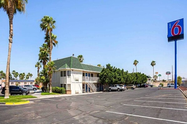 A motel with a parking lot, a building with a green roof, and palm trees. - 2 Queen Beds | Premium, Micfridge (Yuma AZ)