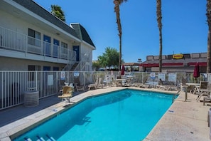 A swimming pool with lounge chairs, a building with balconies, and palm trees. - 2 Queen Beds | Premium, Micfridge (Yuma AZ)