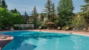 A swimming pool with lounge chairs and umbrellas, surrounded by trees and buildings. - Experience the Ultimate Family Getaway at Sheraton Mountain Vista's 2-Bd Lockoff (Avon)