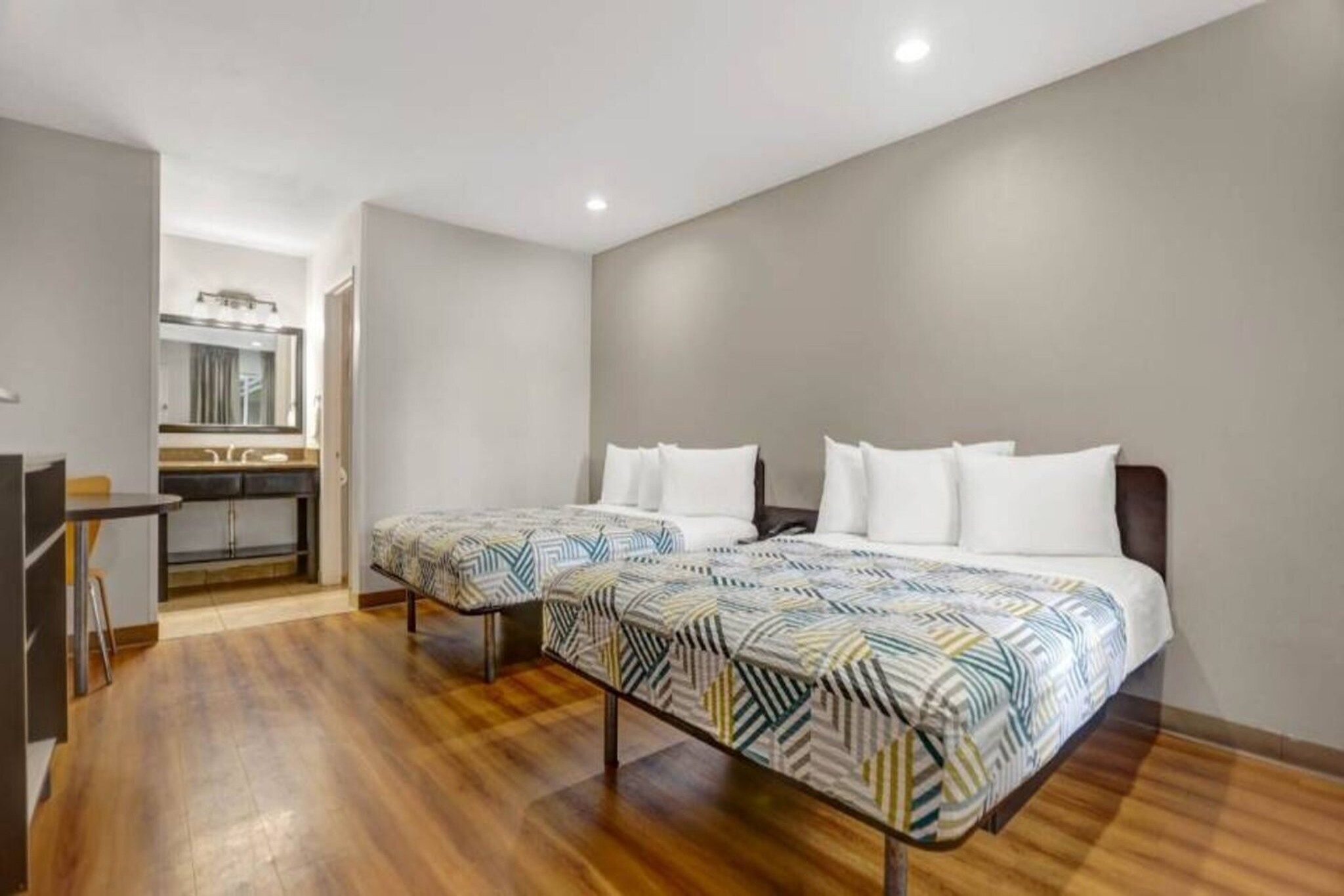 Ein Hotelzimmer mit zwei Betten, einer Küchenzeile und Holzboden.