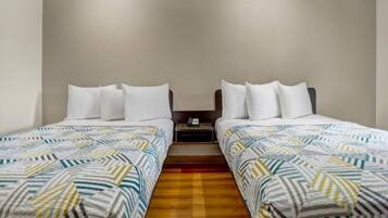 Ein Doppelzimmer mit zwei Betten, jeweils mit gemusterten Bettbezügen und weißen Kissen.