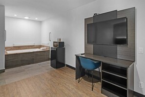 Une chambre moderne équipée d’un lit, d’un bureau, d’une chaise, d’une télévision et d’une petite kitchenette.