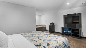 Una habitación de hotel moderna con una cama grande, un escritorio, un televisor y un baño al fondo.