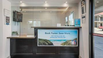 A reception desk with a digital screen displaying a message about booking faster and saving more.