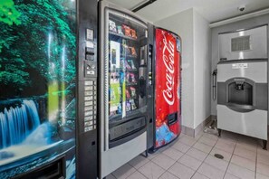 Un distributeur automatique orné du logo Coca-Cola, un distributeur d’eau et une vitrine contenant divers articles.