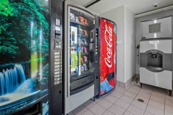 Un distributeur automatique orné du logo Coca-Cola, un distributeur d’eau et une vitrine contenant divers articles.