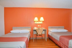 A hotel room with two beds, a desk, and two lamps.