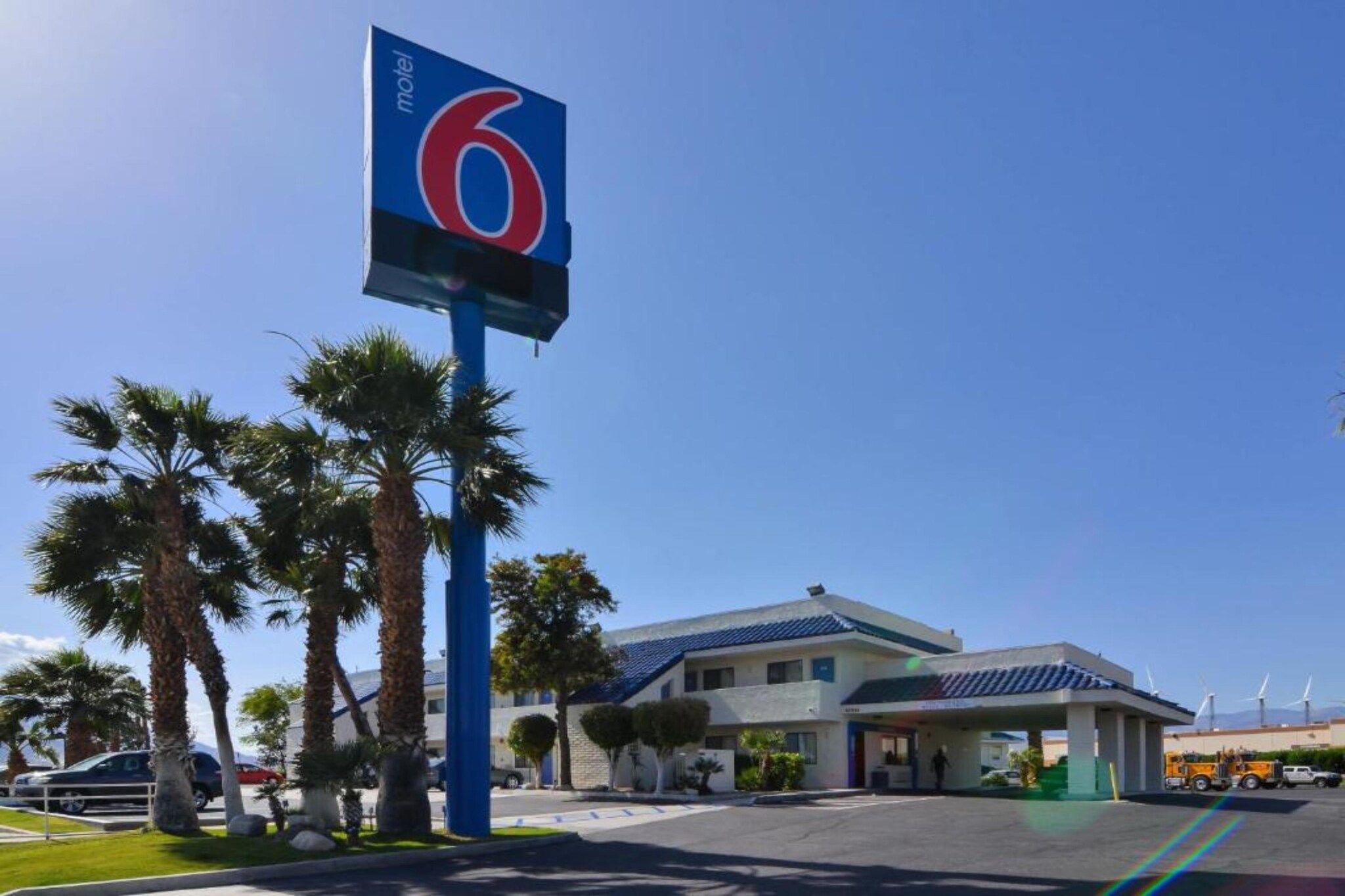 A motel with a prominent sign, palm trees, and a building with a blue roof.
