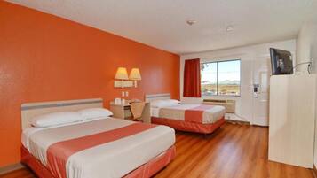 A hotel room with two beds, a desk, a chair, a TV, and a window with a view.