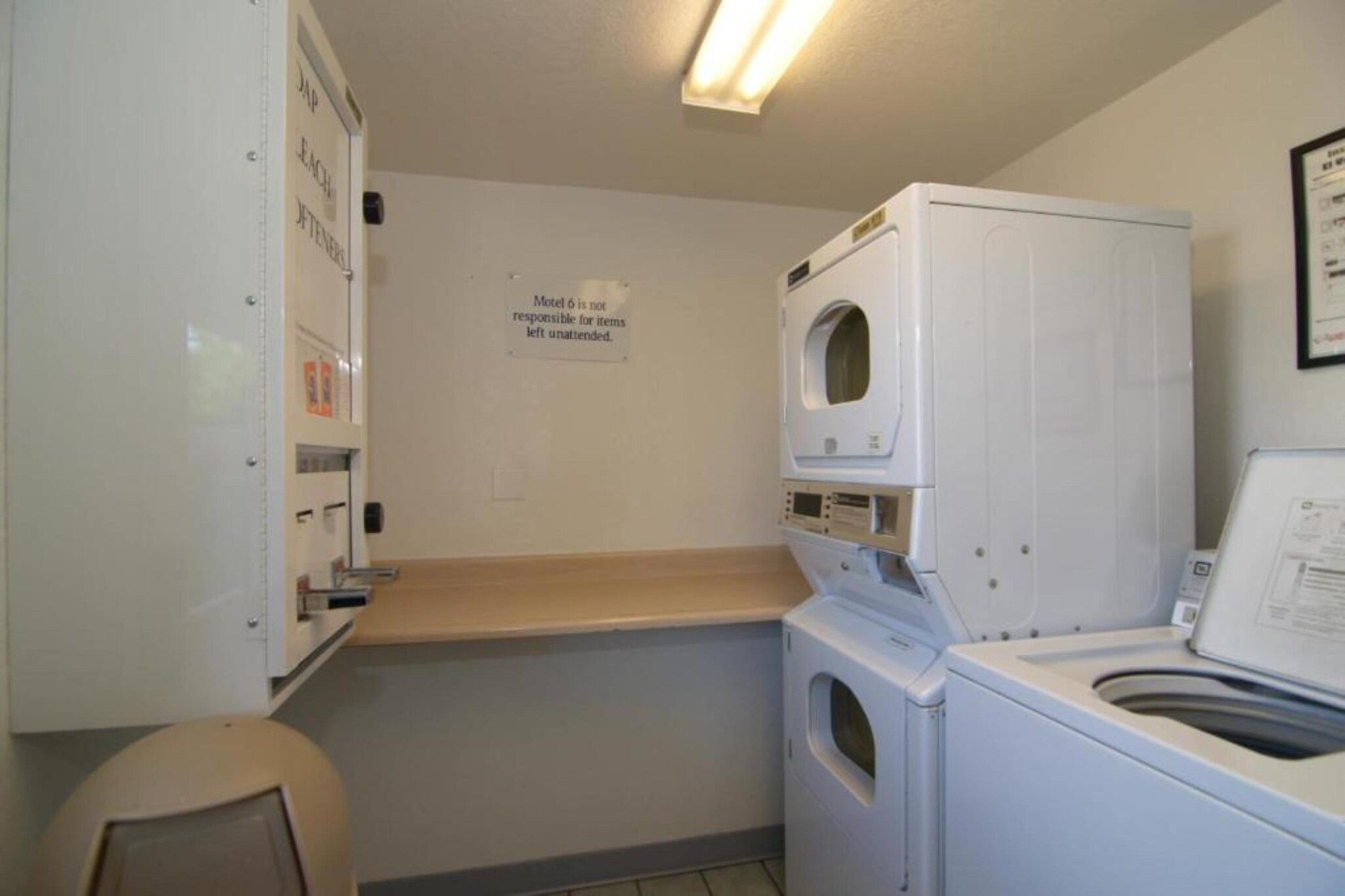 Ein Waschraum mit Waschmaschine, Trockner und einem an der Wand befestigten Schrank mit einem Schild.