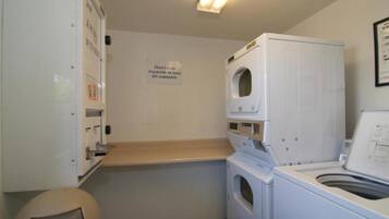 A laundry room with a washing machine, dryer, and a sign on the wall.