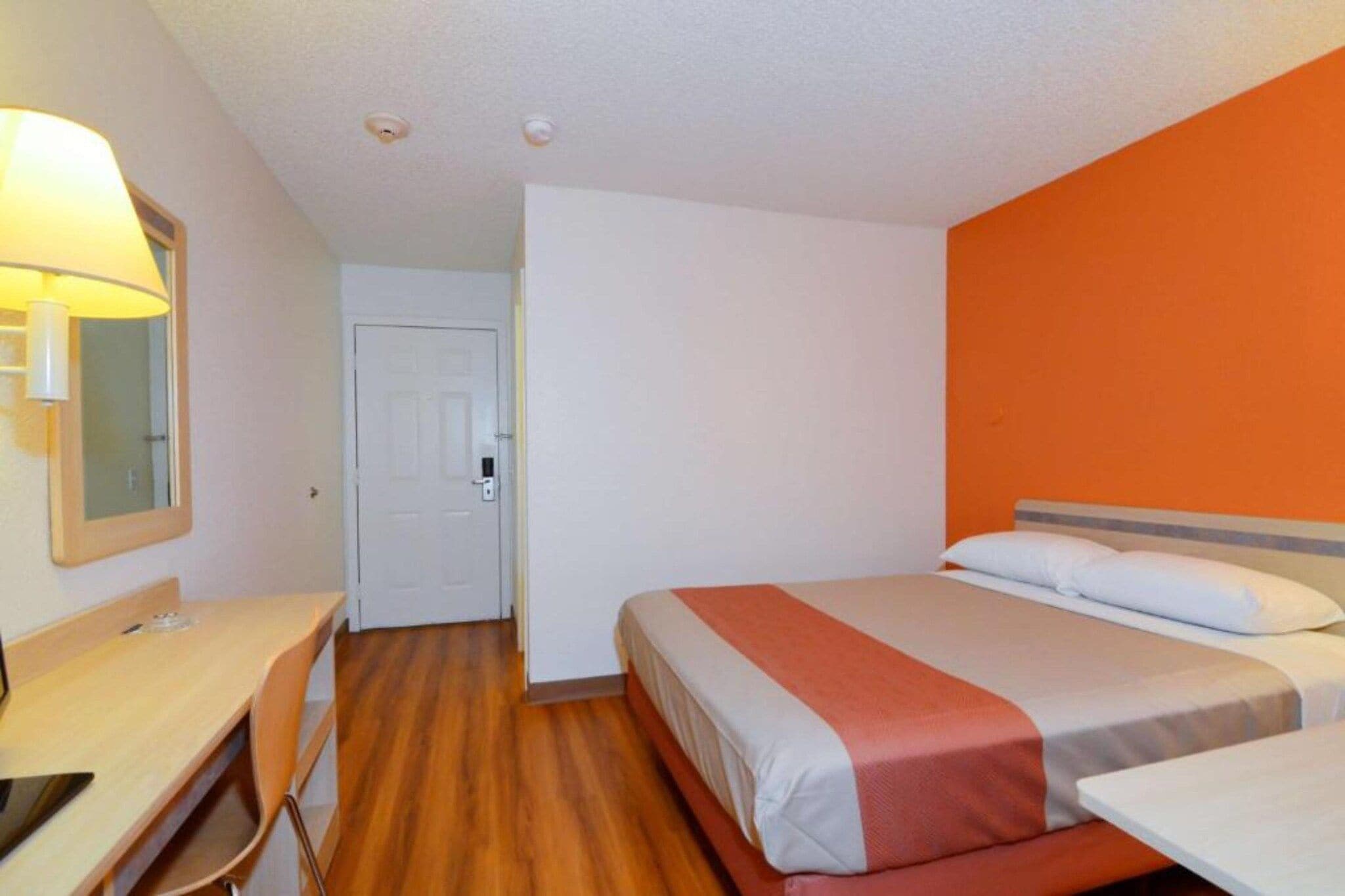 Une chambre d’hôtel avec un lit, un bureau, une chaise et une lampe.