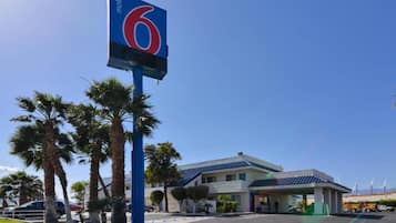 A motel with a prominent sign, palm trees, and a building with a blue roof.