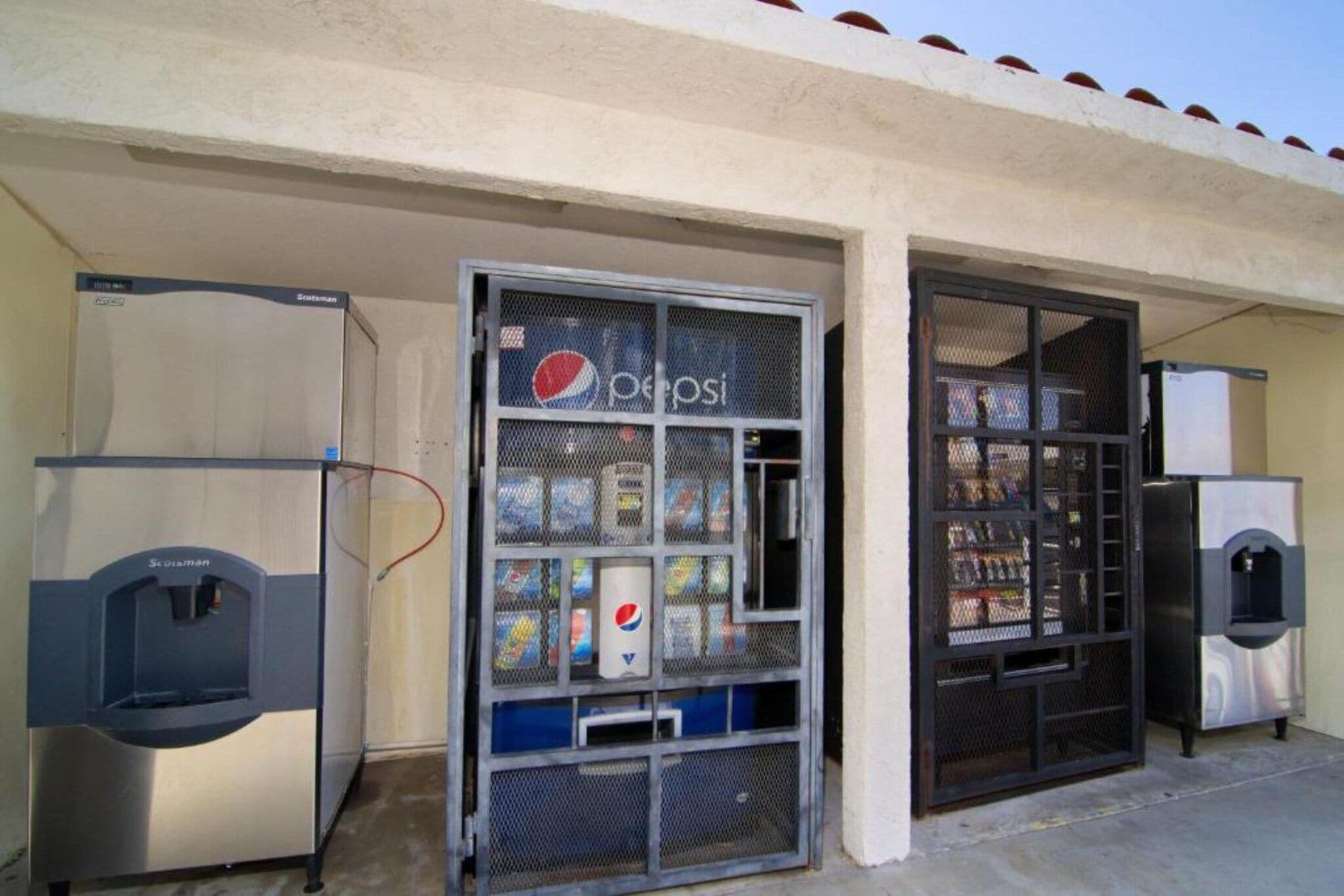 Un espace comprenant un distributeur automatique orné du logo Pepsi, un autre distributeur de la marque Scotman et un appareil réfrigérant.