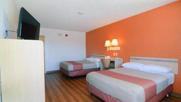 Ett hotellrum med två sängar, en tv och en väggmonterad lampa.