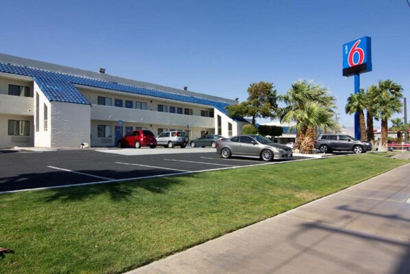 A motel with a parking lot, a building with a blue roof, and a '6' sign indicating the motel name.