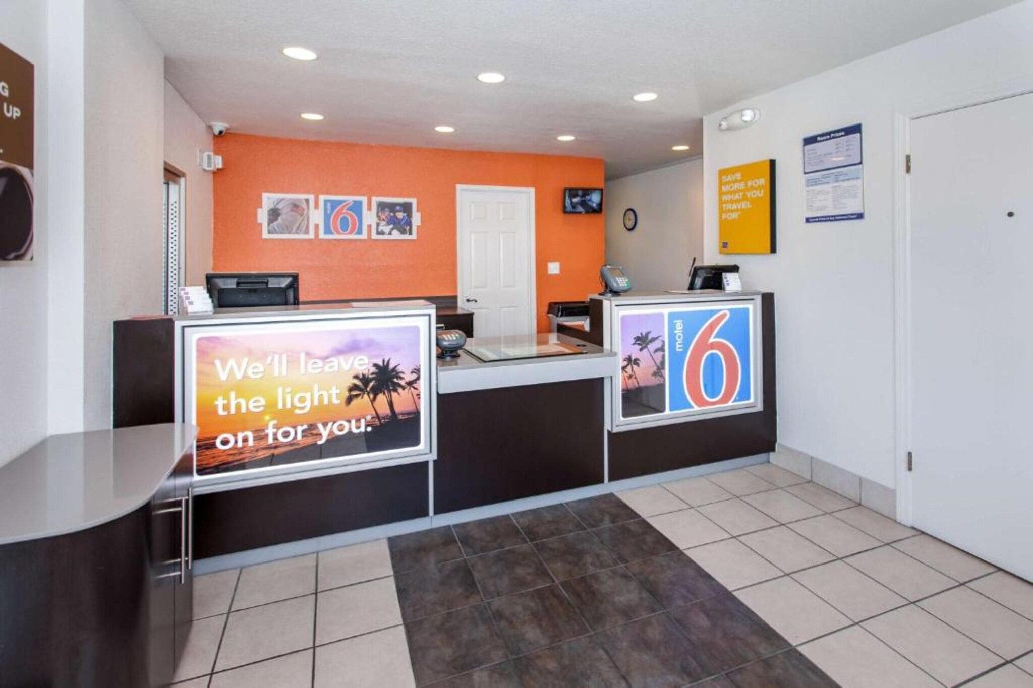 A hotel reception area with a counter, a digital display, and a wall-mounted clock.
