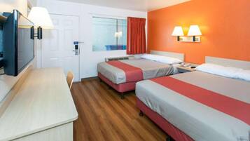 A hotel room with two beds, a desk, a chair, a television, and a window with curtains.