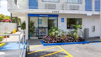A building with a blue entrance, a welcome sign, and a parking sign indicating a disabled parking space.