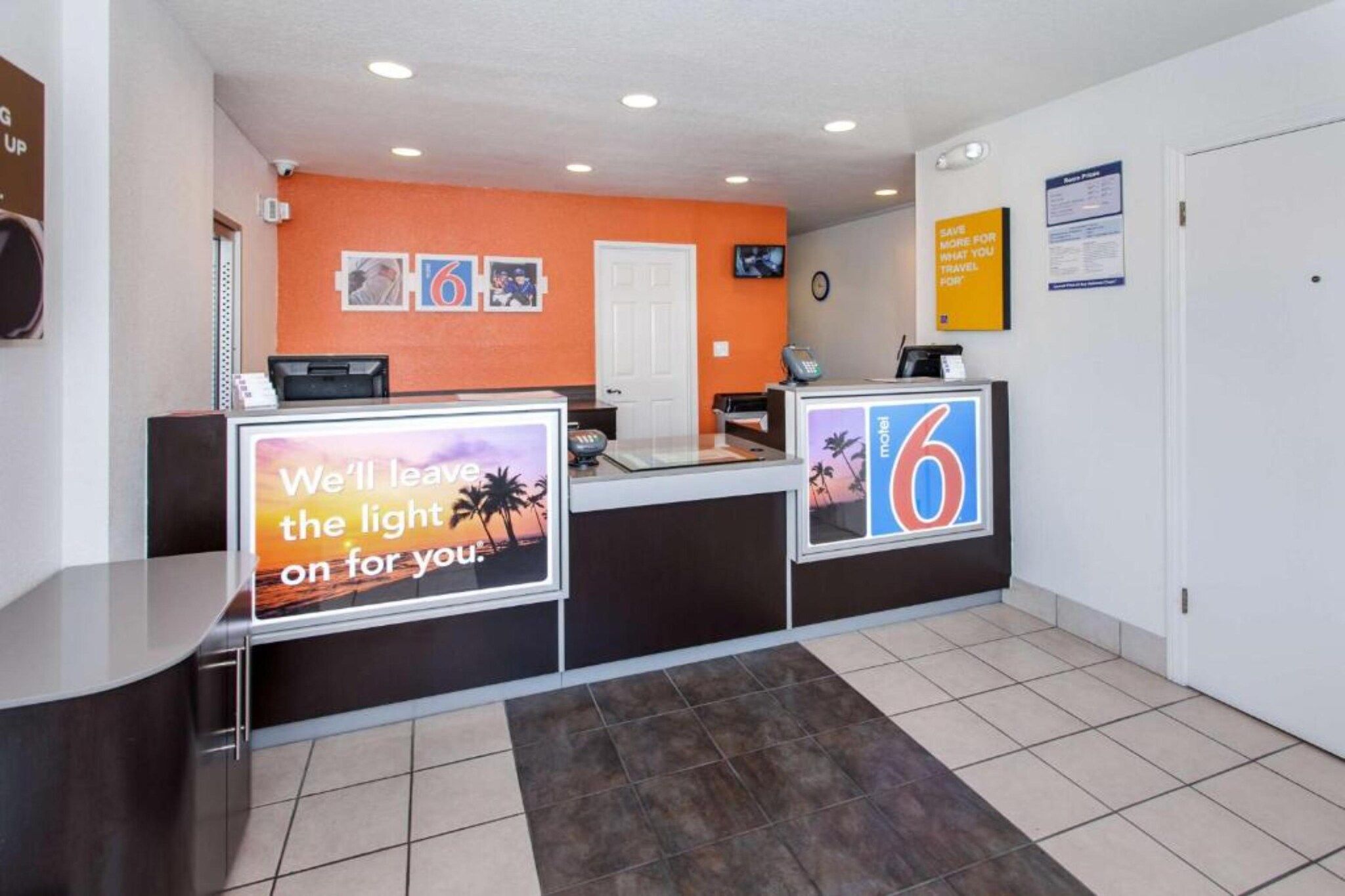 A hotel reception area with a counter, a digital display, and a wall-mounted clock.