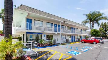 A multi-story motel with a parking lot, marked handicap parking spaces, and a visible entrance.