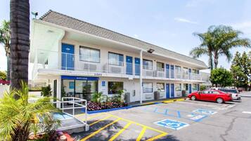 A motel with a parking lot, marked handicapped spaces, and a 'Welcome' sign.