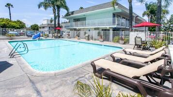 A swimming pool with lounge chairs and a building in the background.