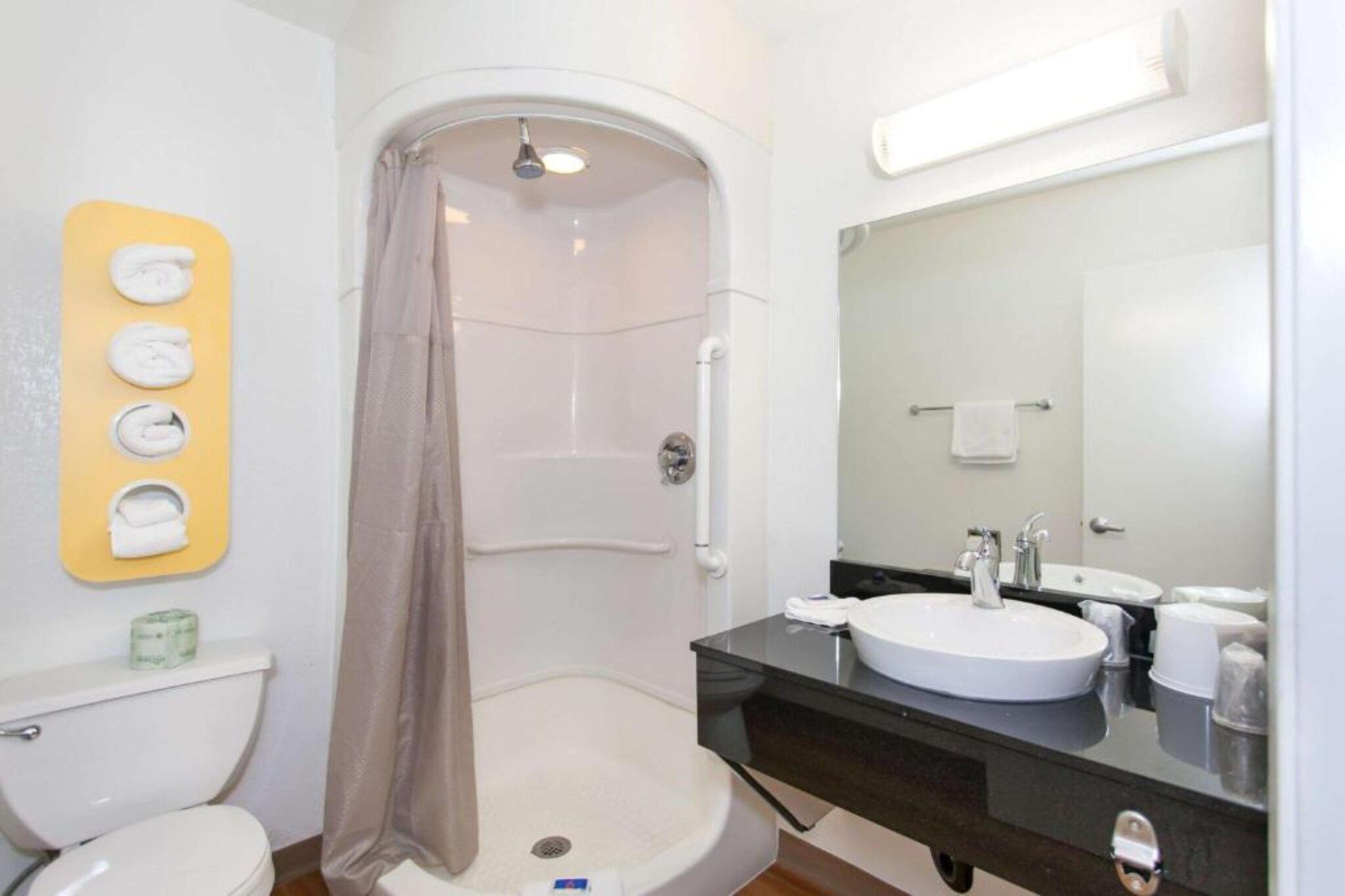 A bathroom with a shower, toilet, sink, and a mirror.