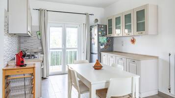 Cozinha moderna com mesa de jantar, cadeiras e geladeira com ímãs.