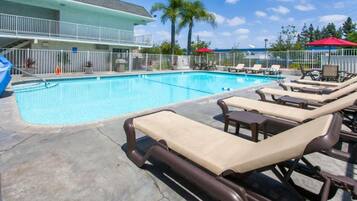 A swimming pool with lounge chairs and a building in the background.