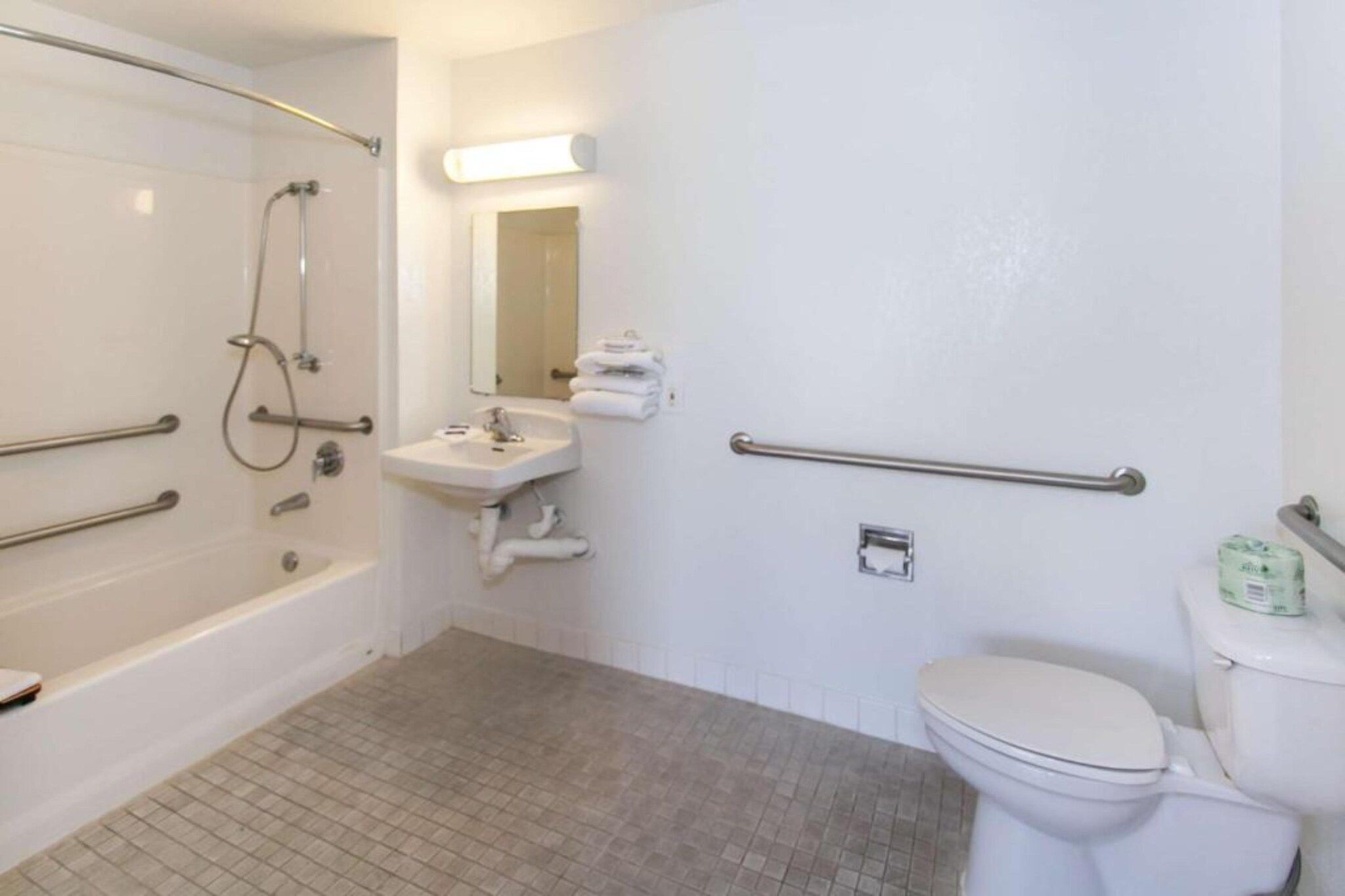 Un baño con bañera, lavamanos, inodoro y barandilla.