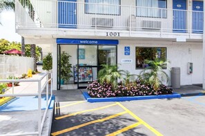 A building entrance with a 'Welcome' sign, a parking sign, and a blue awning. - 1 Full Bed | ADA/RI Shower (Rosemead)