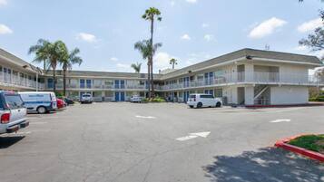 A motel with multiple rooms, a parking lot, and a few parked vehicles.