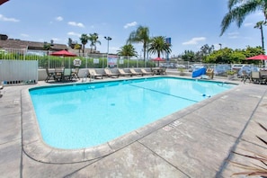 A rectangular swimming pool with a tiled deck, surrounded by a white fence, and equipped with lounge chairs and umbrellas. - 2 Full Beds | Mini Fridge (Rosemead)