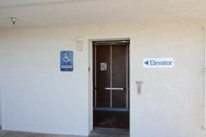 Eine Aufzugstür mit einem Schild, das daraufhinweist, dass sie für Rollstuhlfahrer reserviert ist.