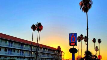 A motel with a red roof, multiple floors, and a sign indicating room availability.