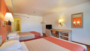 Ein Hotelzimmer mit zwei Betten, einem Schreibtisch, einem Fernseher und einem Spiegel.