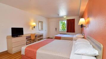 Habitación de hotel con dos camas, un escritorio, un televisor y una ventana con cortinas.
